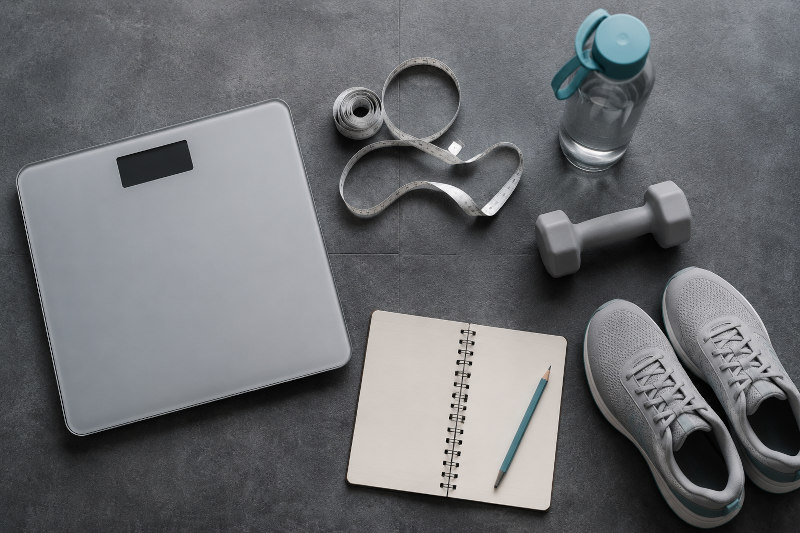 Running for Weight Loss weighing scales dumbbell water bottle notebook and trainers Running for Weight Loss weighing scales dumbbell water bottle notebook and trainers